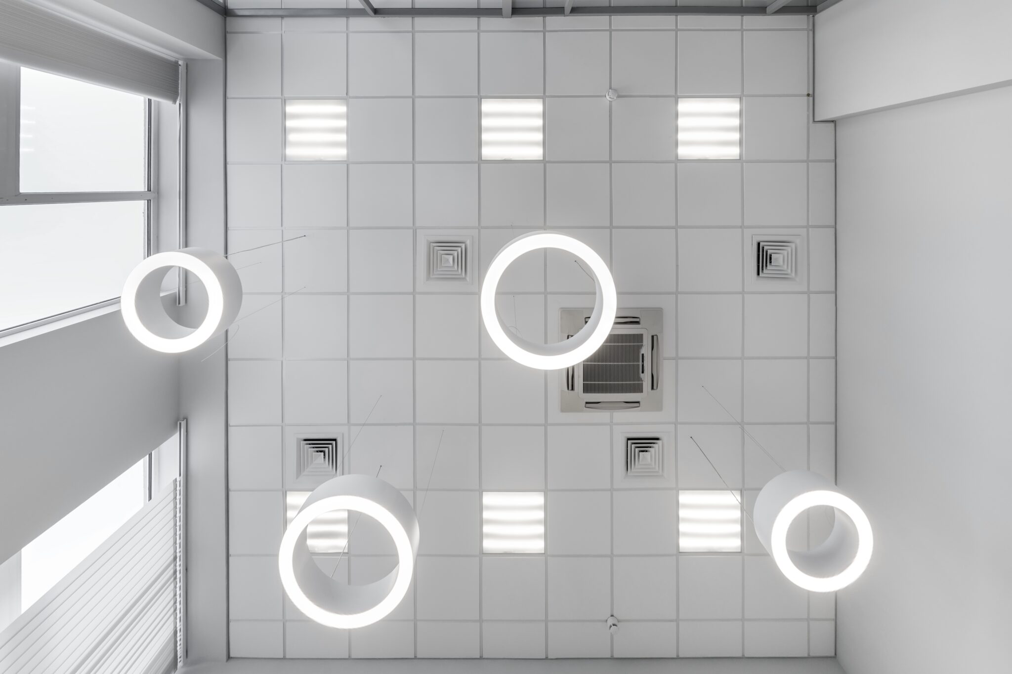 cassette suspended ceiling with square and round halogen spots lamps and drywall construction in empty room in apartment or house. Stretch ceiling white and complex shape. Looking up view