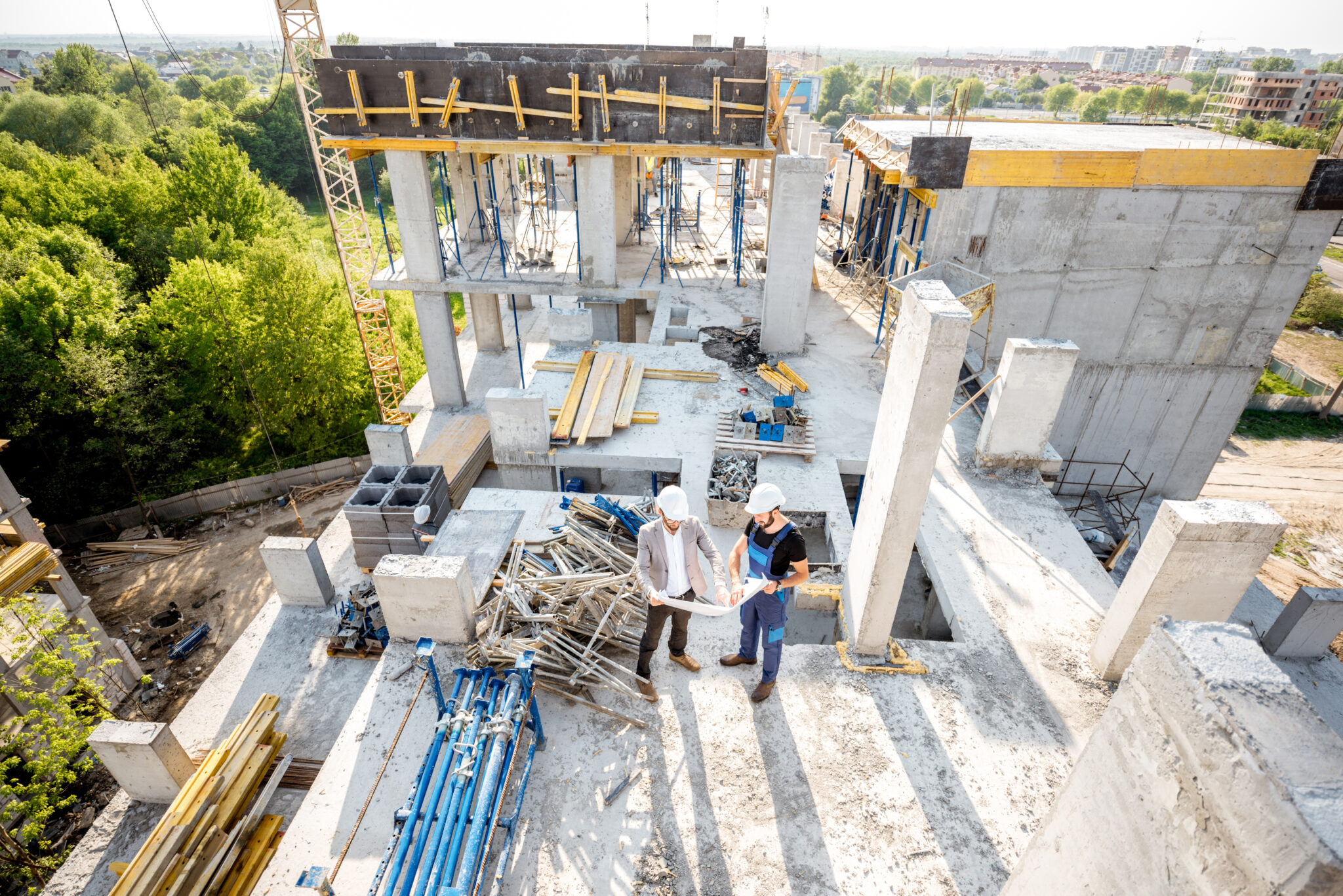 Top view on the construction site of residential buildings during the construction process with two workers standing with drawings